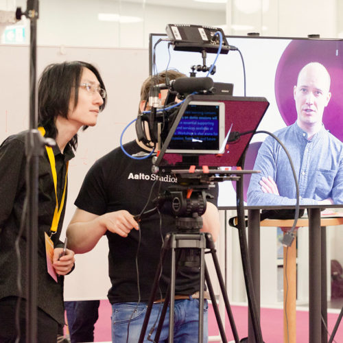 Students and teachers testing a video setup with a teleprompter.